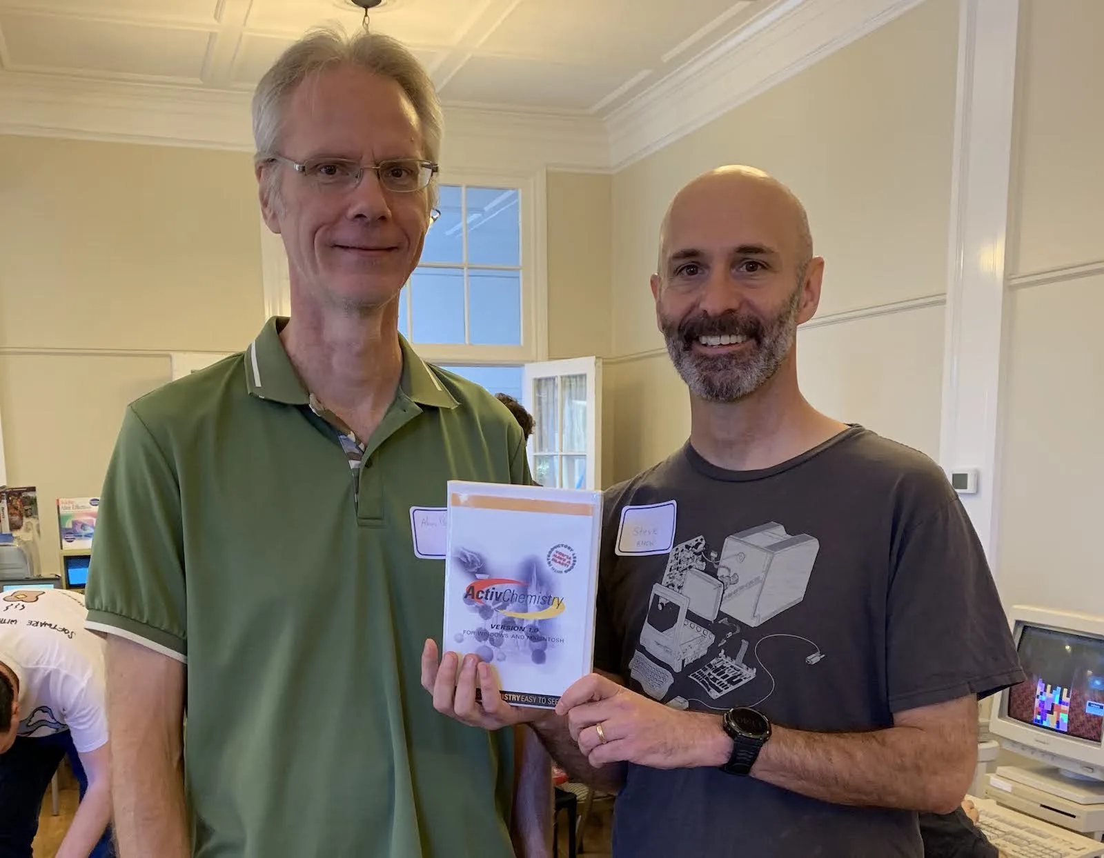 Two attendees holding vintage Mac software